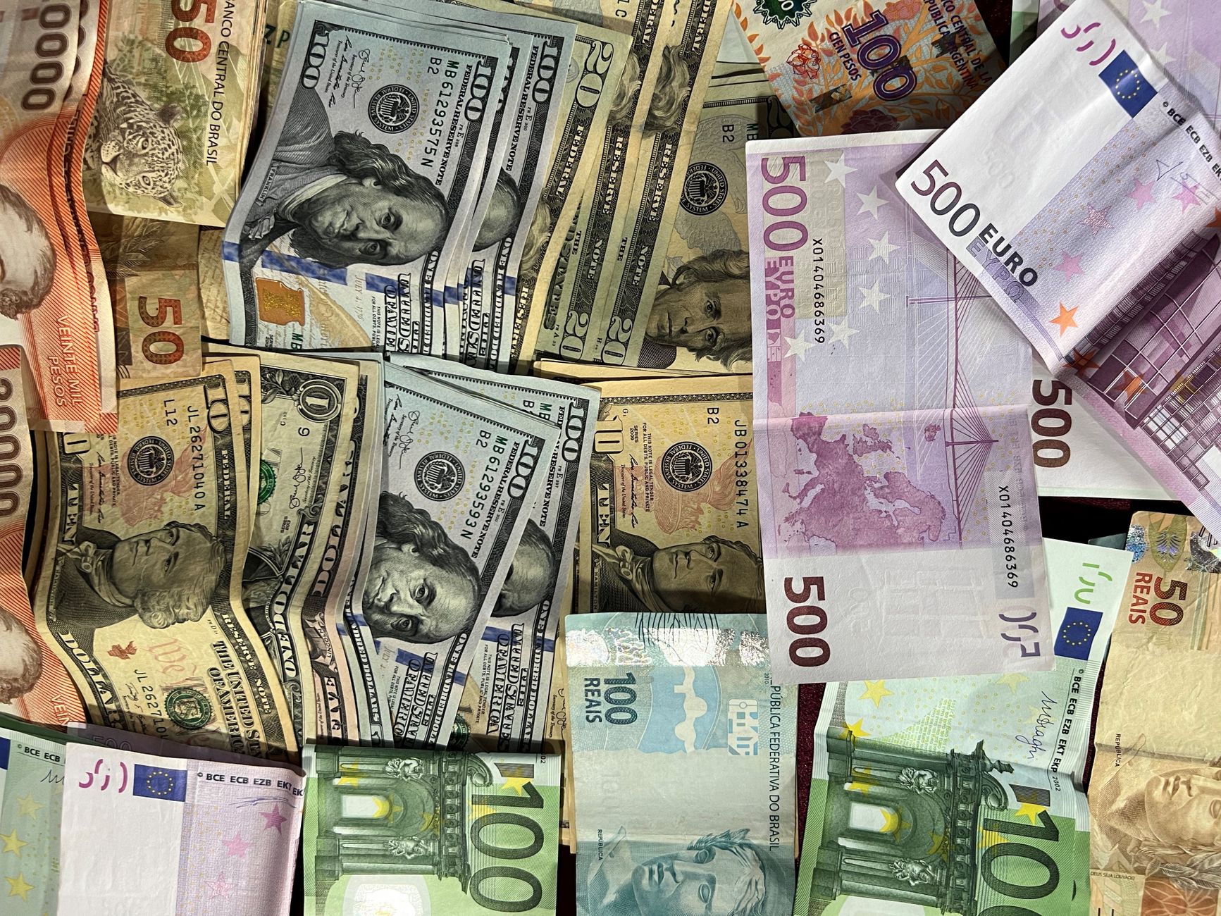 Cédulas de Real e gráficos econômicos representando o cenário do PIB brasileiro.
